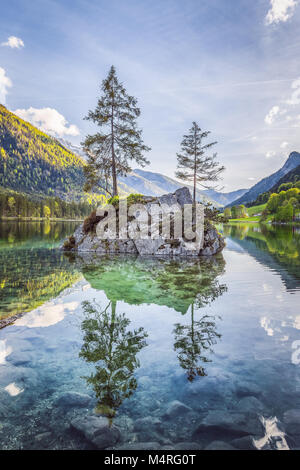 Belle scène d'arbres sur une île de roche dans un paysage idyllique au charmant lac Hintersee avec ciel bleu et nuages dans l'été, parc national de Berchtesgaden Banque D'Images