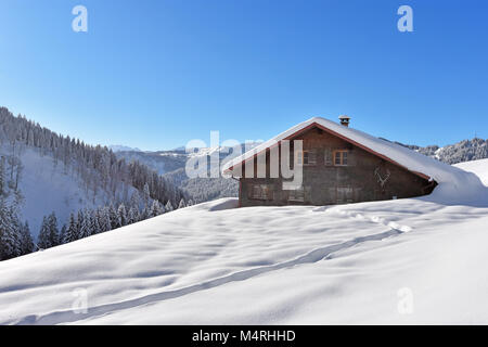 Profondément le paysage couvert de neige dans les Alpes avec Allgaeu forêts et un chalet de montagne à une belle journée d'hiver. La Bavière, Allemagne Banque D'Images