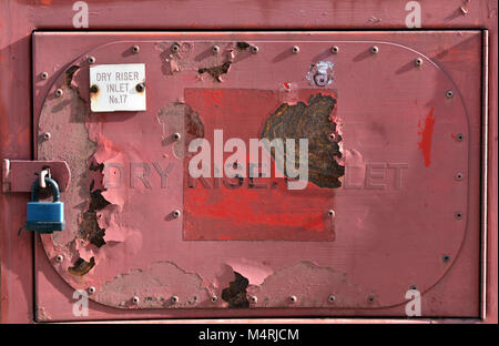 Une peinture feuilletée peint couleur rouille sur un feu d'entrée de montage à sec à l'extérieur d'un immeuble de bureaux dans le centre de Londres. rusty et l'équipement de sécurité n'est pas oxydée. Banque D'Images