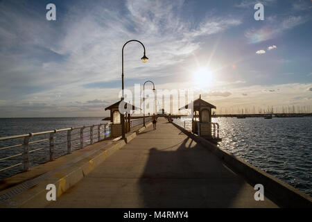 St Kilda, Australie : 15 mars 2017 : St Kilda Pier au coucher du soleil avec l'emblématique petit pavillon bleu à la fin de la marina. Banque D'Images