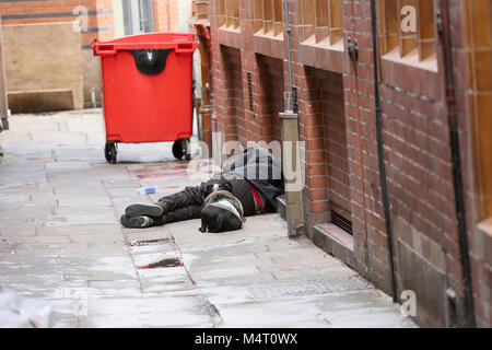 Manchester, UK. Feb 17, 2018. Les sans-abri a augmenté en raison de frais de logement. Un Staffordshire Bull Terrier portant un manteau monte la garde de son propriétaire qui est couché dans une rue de Manchester, 17 février 2018 (C)Barbara Cook/Alamy Live News Banque D'Images