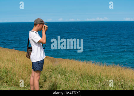 Un jeune homme à prendre des photos près de l'océan avec un appareil photo reflex analogique Banque D'Images