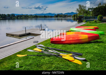 Rangée de kayaks et de pagaies en attente sur un quai de Mirror Lake dans la région de Lake Placid, New York, USA. Banque D'Images