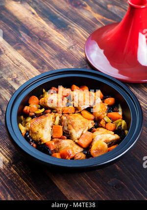 Tagine avec le poulet cuit et les légumes. Fond de bois. Banque D'Images