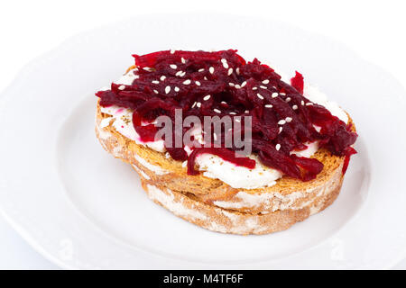 Toast sain avec fromage féta betteraves et graines de sésame sur une plaque, sur fond blanc Banque D'Images