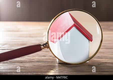 Close-up of a House Model vu à travers une loupe sur table en bois Banque D'Images