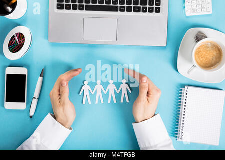 L'homme d'une part protéger le papier découpé Figure humaine sur Office 24 Banque D'Images