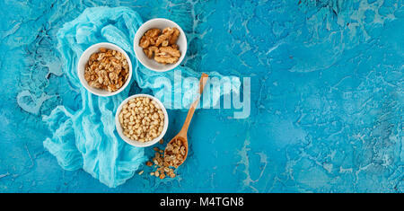 Ensemble de différents types de noix - les arachides en coque, noix de pin sur fond bleu Banque D'Images