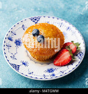 Muffin, gâteau avec les baies fraîches sur une assiette. Fond bleu. Banque D'Images