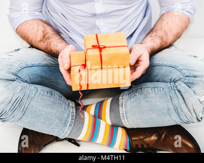 Bel homme drôle en chaussettes et chaussures élégantes avec un cadeau pour son être cher Banque D'Images