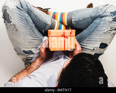 Bel homme drôle en chaussettes et chaussures élégantes avec un cadeau pour son être cher Banque D'Images