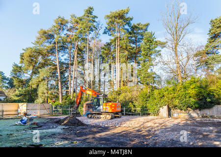 Grosse orange mechanical digger debout sur une plate-forme de noyau dur de moellons de brique sur un site de démolition préparation de réaménagement résidentiel Banque D'Images