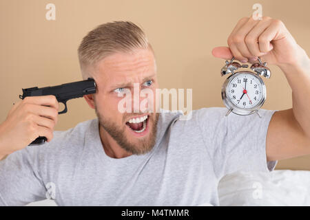 Close-up of a Angry Young Man Holding Gun et Réveil Banque D'Images