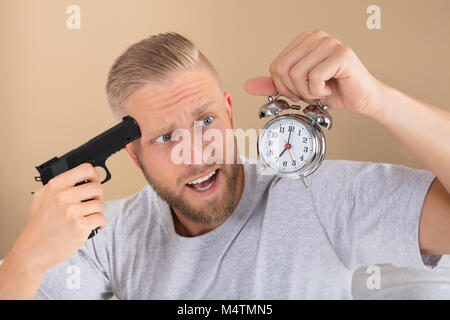 Close-up of a Angry Young Man Holding Gun et Réveil Banque D'Images