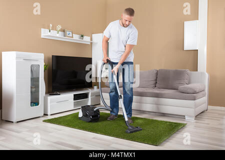 Jeune homme Tapis de Nettoyage avec aspirateur dans la salle de séjour Banque D'Images