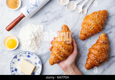 Des croissants, des ingrédients avec woman's hand holding croissant frais. Vue d'en haut. Copy space Banque D'Images