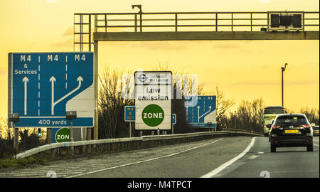 Panneau de zone à faibles émissions en regard de la bande d'arrêt d'urgence par Transport for London (TFL, plus les panneaux de voies de l'autoroute M4, à l'ouest de London, England, UK. Banque D'Images