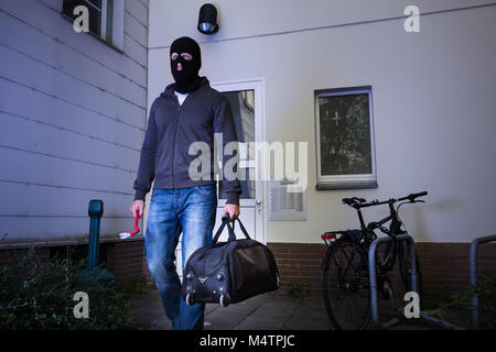 Cambrioleur dans Black Mask s'échapper avec sac à main après avoir volé à partir de la chambre Banque D'Images