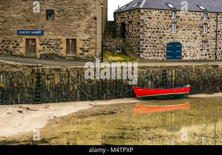 Rouge Petit bateau à rames à marée basse, port pittoresque, Portsoy, Aberdeenshire, Scotland, UK, avec de l'eau réflexions et bâtiments historiques Banque D'Images