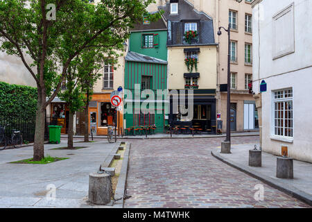 Vue sur petite rue pavée avec petit bar, boutiques et l'architecture typique de Paris, France. Banque D'Images