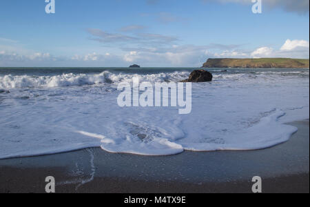 L'eau blanche avec le fracas des vagues sur une plage de sable et rochers, à Cornwall. Banque D'Images