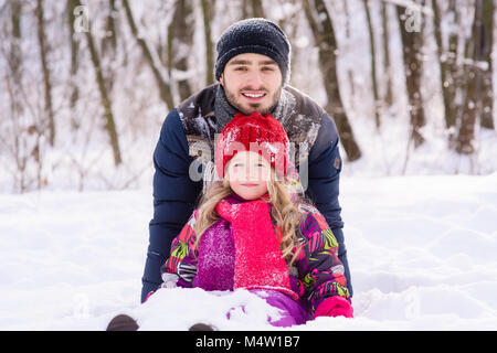 Petite fille et père posant au cours de jeu avec la neige Banque D'Images