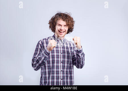 Jeune homme frisé surpris, joyeuse émotion sur son visage. Banque D'Images