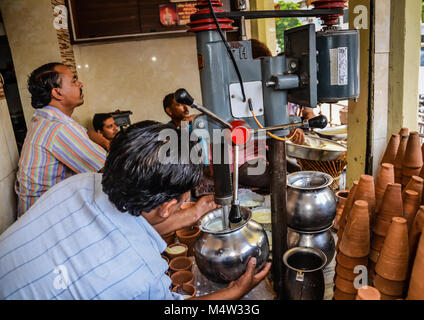 Faire de lassi à la mangue sur une machine industrielle à Jaipur, Inde. Le yogourt boissons est servi dans des tasses d'argile. Banque D'Images