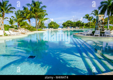 L'une des plus importantes des Caraïbes, cette immense piscine vue sur une plage de sable blanc. La piscine d''eau salée est entourée de chaises longues blanc et grand pa Banque D'Images