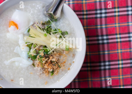 Bouillie de riz dans un bol d'œufs hachés de porc avec une impression de fond tartan Banque D'Images