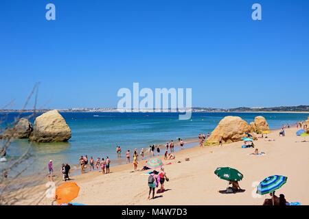 Les touristes se détendre sur la plage avec de grosses roches et de vues à travers l'océan vers le littoral, Praia da Rocha, Algarve, Portugal, Europe. Banque D'Images