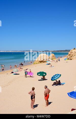 Les touristes se détendre sur la plage avec de grosses roches et de vues à travers l'océan vers le littoral, Praia da Rocha, Algarve, Portugal, Europe. Banque D'Images