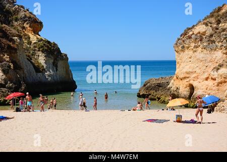 Les touristes se détendre sur la plage par deux gros rochers avec vue sur l'océan, Praia da Rocha, Algarve, Portugal, Europe. Banque D'Images