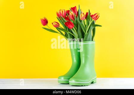 Tulipes rouges dans des bottes en caoutchouc Banque D'Images