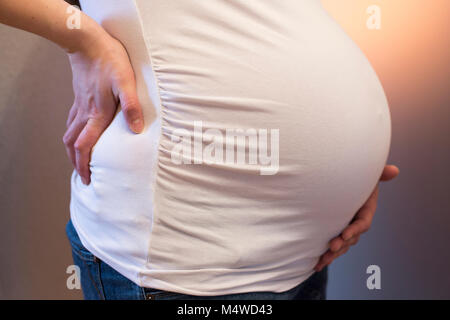 Une femme enceinte tenant son dos et son ventre Banque D'Images