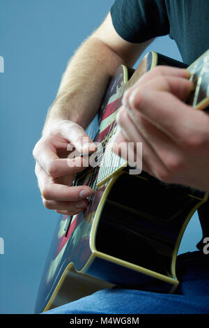 Mains d'un jeune homme jouant de la guitare avec un drapeau américain Banque D'Images