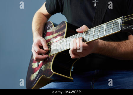 Mains d'un jeune homme jouant de la guitare avec un drapeau américain Banque D'Images