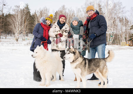 Portrait de deux jeunes couples qui posent avec les chiens husky appréciant belle journée d'hiver à l'extérieur Banque D'Images