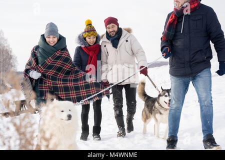 Groupe de jeunes marcher deux magnifiques chiens en laisse tout en appréciant belle journée d'hiver dans les bois Banque D'Images