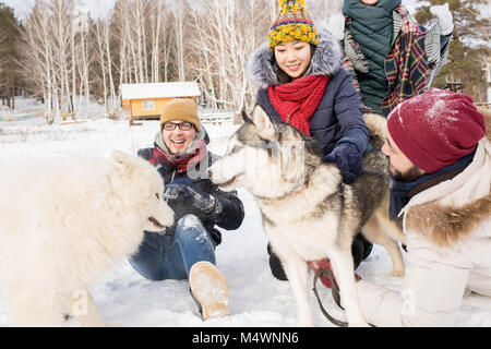 Portrait de quatre jeunes gens heureux de jouer avec chiens dans les bois d'hiver à l'extérieur Banque D'Images