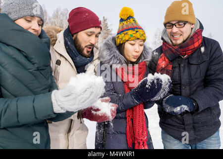 Portrait de quatre jeunes amis s'amuser en plein air, sur la journée d'hiver maintenant des poignées de neige jouer snowball fight Banque D'Images