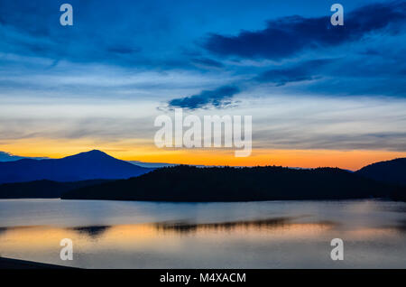 Lueur de soleil derrière les montagnes de l'Adirondack réfléchi à Lake Placid dans l'État de New York. Banque D'Images