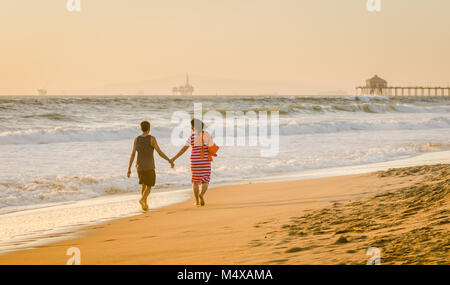 Un couple prend une heure d'or promenade sur la rive edge à Huntington Beach en Californie. Banque D'Images