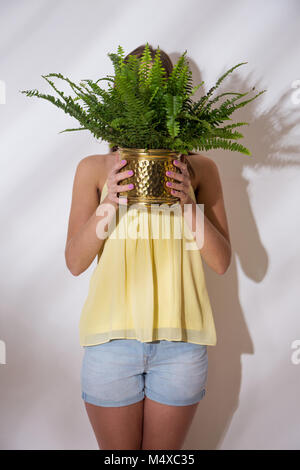 Une fille est holding pot avec une fougère Banque D'Images