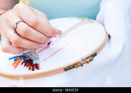 Broderie main de femme les anges dans le cerceau, jeune fille brode un motif sur le tissu blanc, sweetie brunette engagés dans la couture Banque D'Images