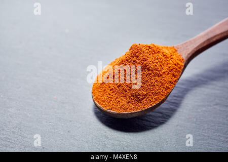 Shichimi poivre dans cuillère en bois sur la plaque en pierre noire Banque D'Images