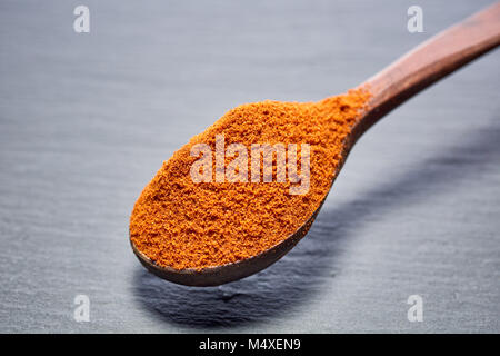 Shichimi poivre dans cuillère en bois sur la plaque en pierre noire Banque D'Images