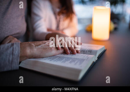 Une petite fille méconnaissable et sa grand-mère reading bible à la maison. La famille et des générations futures. Banque D'Images