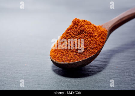 Shichimi poivre dans cuillère en bois sur la plaque en pierre noire Banque D'Images