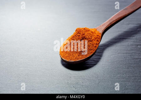 Shichimi poivre dans cuillère en bois sur la plaque en pierre noire Banque D'Images